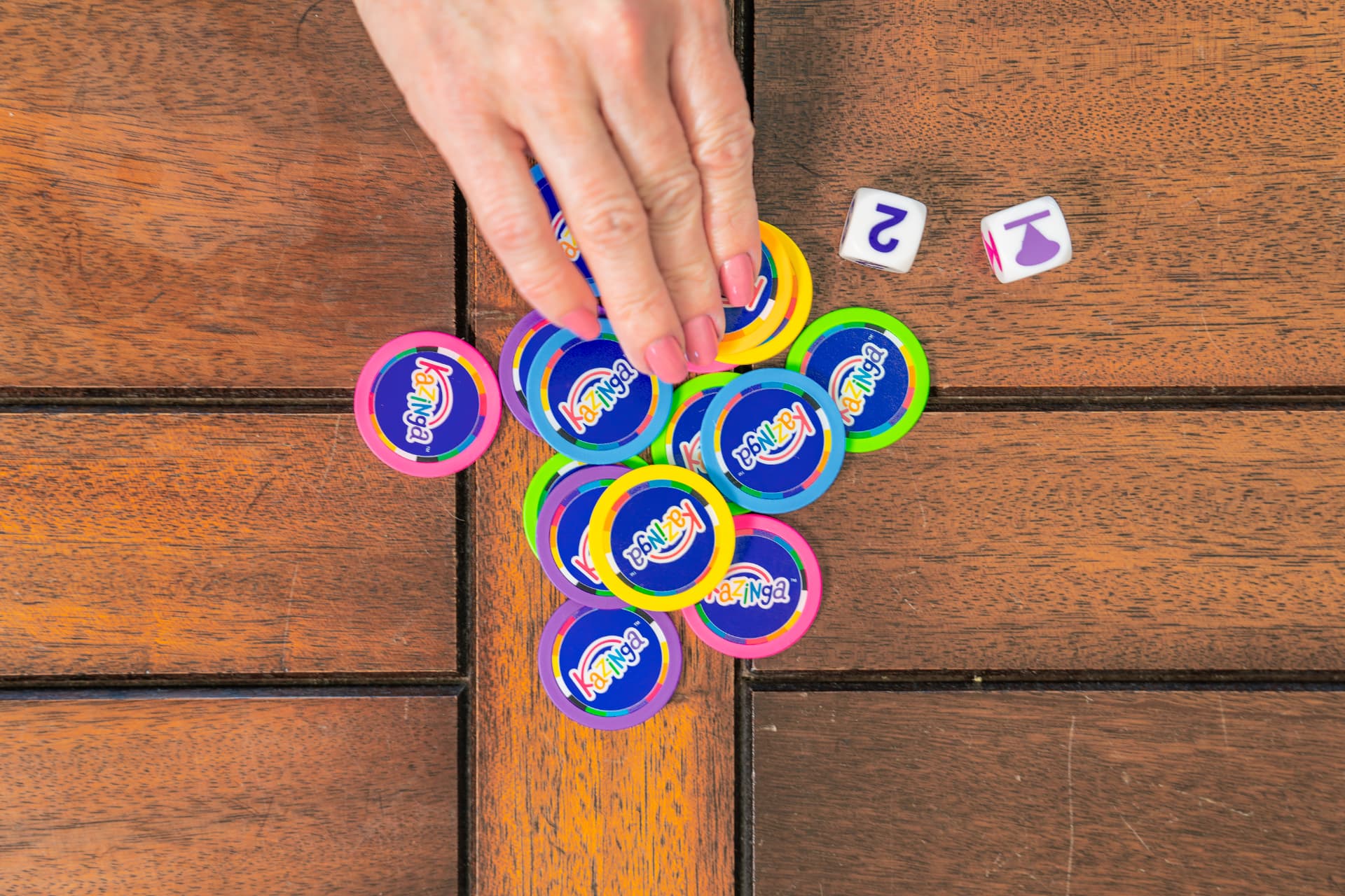 A hand sweeping a pile of Kazinga chips on a wooden table